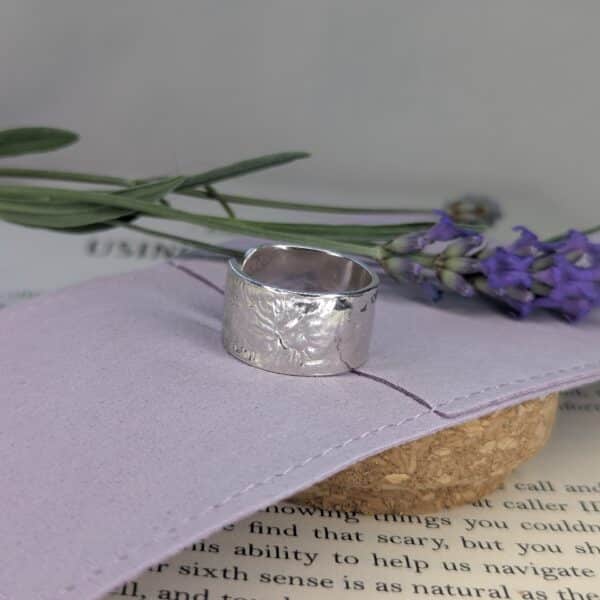 Chunky sterling silver ring placed on a cloth jewellery bag with lavender in the background