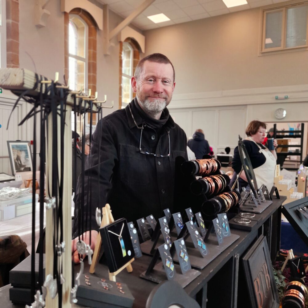 man stood behind an indoor jewellery stall