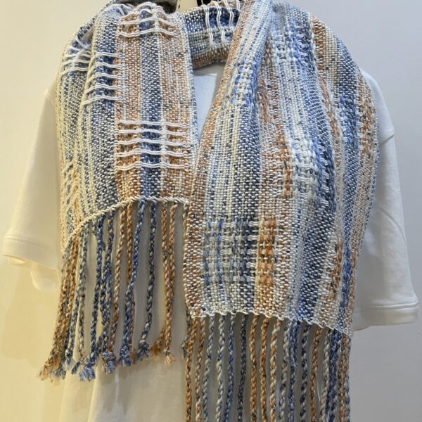 A wool and cotton scarf in blues, peach and white colours with a delicate texture in alternate blocks By Hook & Heddle