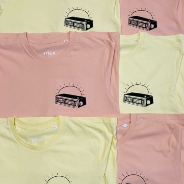 Light yellow and peach coloured t-shirts that feature a left breast print of a retro alarm clock, with sun in the backgroud