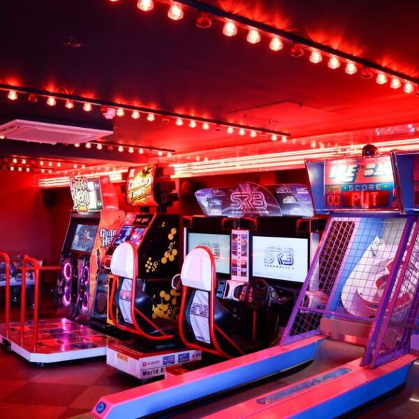 a bright red neon lit room with arcade games and a small bowling ally inside the beeston social