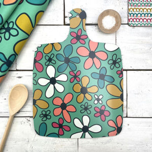 A colouful chopping board with a retro floral pattern in turquoise, mustard and coral