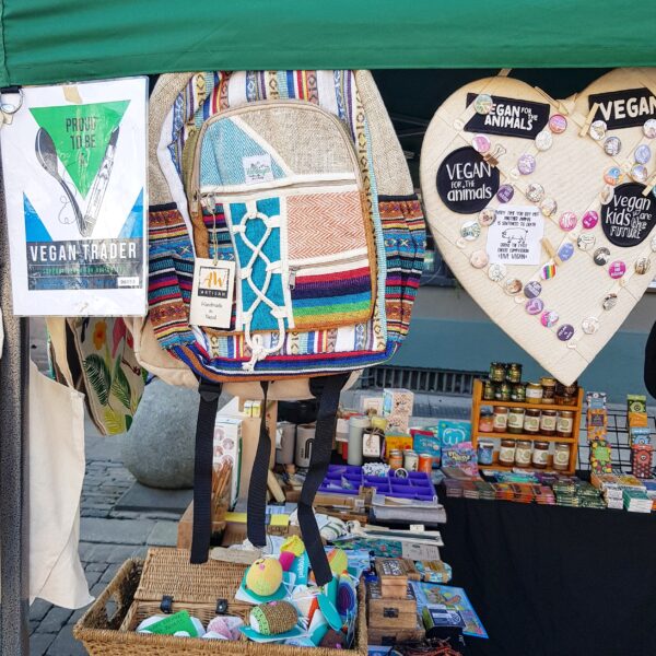 Front on short of Dash Vegan's market stall with a selection of colourful bags, pin badges and the Vegan Traders Union sign displayed.