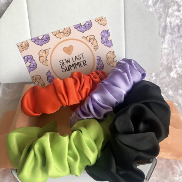 Four satin scrunchie headbands: bright orange, lime green, lilac and black
