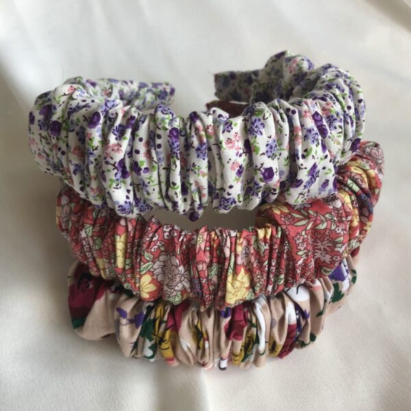 Three Floral cotton regular size scrunchie headbands in the following colours: white with lilac floral, coral with yellow floral, and beige with multi colour floral