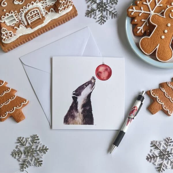 Greetings card featuring a Badger print, on a table surrounded by gingerbread.