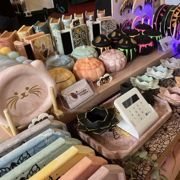 A market stall display featuring pumpkin shaped jars, large trays and book jewellery boxes in pastel colours of the rainbow