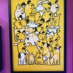 a framed screen print on yellow paper with black and white dog illustration