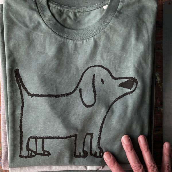 a folded t-shirt with a dog illustration with a hand reaching out to touch it