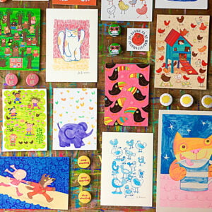 Overhead view of Prints and badges by Jo Brown laid out on a paint marked wooden surface