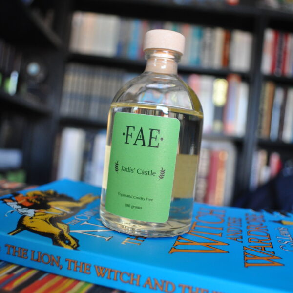 A reed diffuser (without reeds) in the scent Jadis' Castle, sat on top of a book. By Fae Candle Co