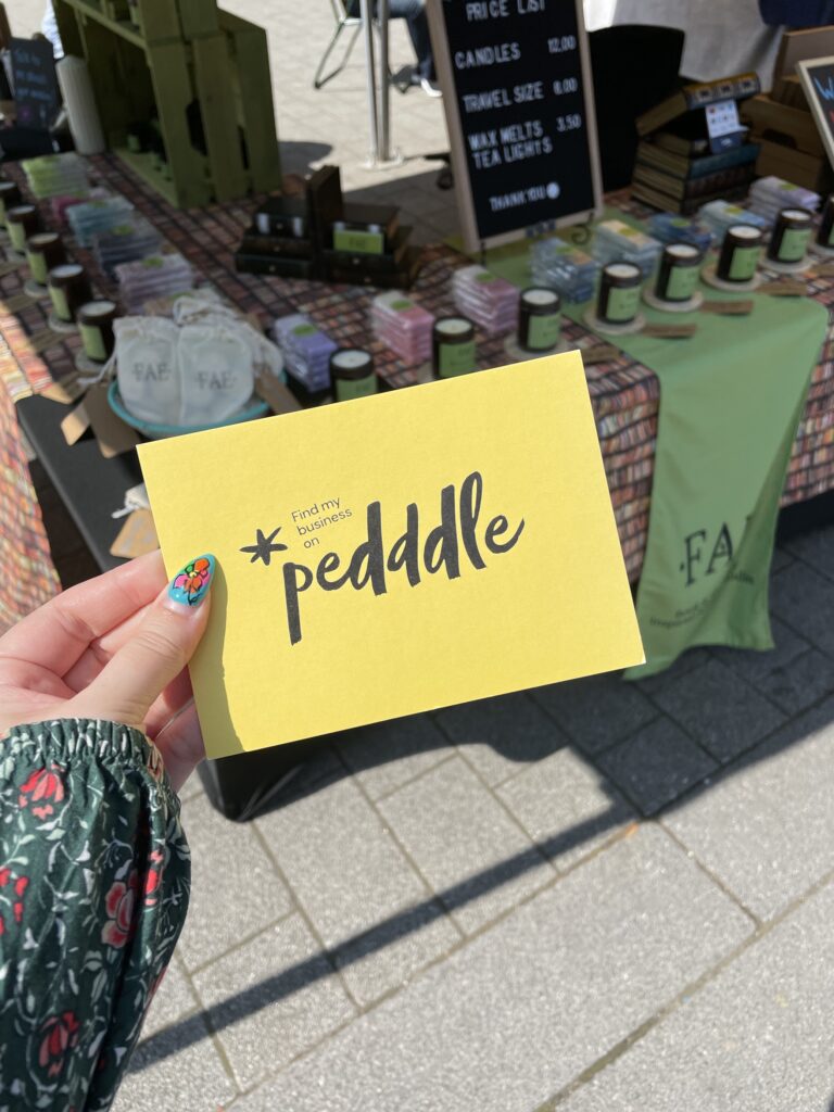 A Pedddle board being held up in front of a Fae Candle Co. stall. successful Pedddle stallholders.