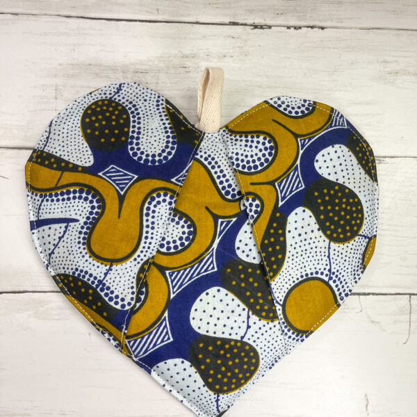 An African-inspired heart-shaped pot holder featuring vibrant colors and intricate patterns, ideal for adding a touch of culture and style to your kitchen decor. The pot holder is crafted with meticulous attention to detail, showcasing traditional African design elements and providing both functionality and aesthetic appeal.