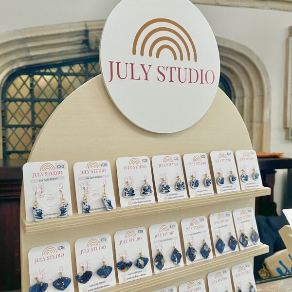 Wooden arch earrings display with a variety of clay earrings on display, July Studio Creations