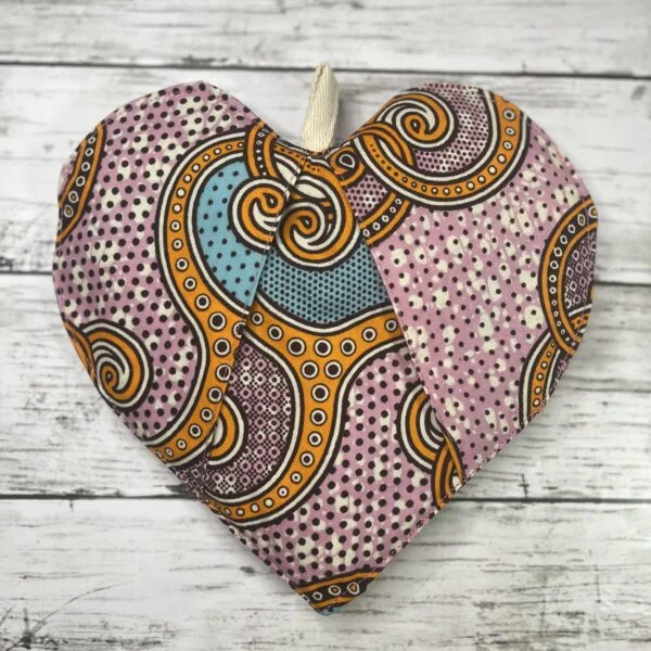 An African-inspired heart-shaped pot holder featuring vibrant colors and intricate patterns, ideal for adding a touch of culture and style to your kitchen decor. The pot holder is crafted with meticulous attention to detail, showcasing traditional African design elements and providing both functionality and aesthetic appeal.