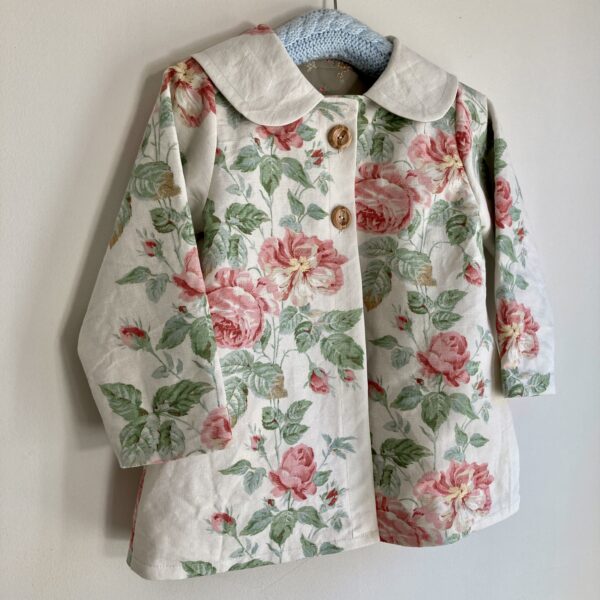 Child’s jacket in vintage roses fabric on a cream background. Traditional style coat with a round collar and wooden buttons, Happy Hedgehog Designs