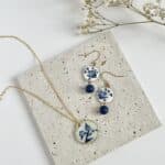 A flat lay pair of blue and white China floral earrings and necklace
