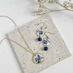 A flat lay pair of blue and white China floral earrings and necklace