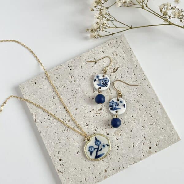 A flat lay pair of blue and white China floral earrings and necklace