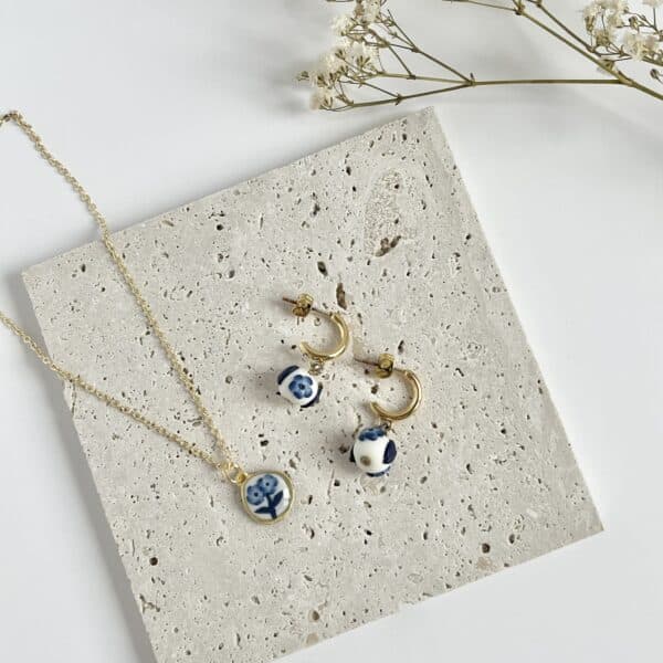 A flat lay pair of blue and white China floral earrings and necklace