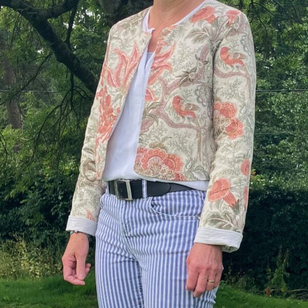 A woman wearing a cropped jacket in a vintage cream & burnt orange swirly floral design fabric. Handmade by Happy Hedgehog Designs