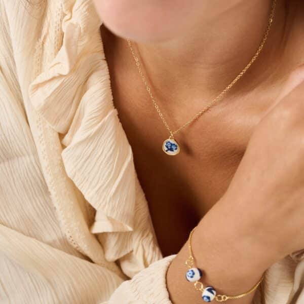 female model wearing a dainty blue and white floral necklace and a dainty blue and white floral bracelet