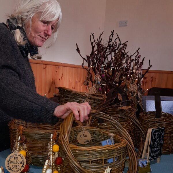 Image os a lady setting up her willow baskets on her display at one of the markets in the Village Hall