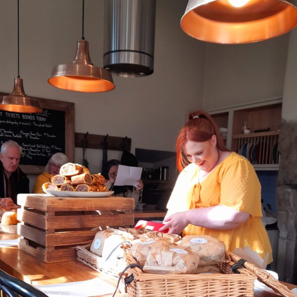 Lady in a yellow t shirt preparing sandwiches and cakes in the Gatehouse kitchen.