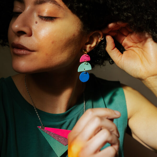 woman with curly black hair wearing pink turquoise and blue earrings