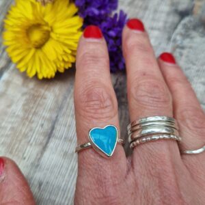 Sterling Silver heart shaped blue surfite ring, UK Size P. Turquoise blue coloured stone with tiny dark blue flecks, heart shaped with shiny, smooth finish, set in a silver surround. Stone measures approximately 10 mm x 14 mm. Ring band is approx. 2 mm wide.