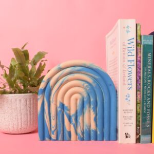 A large blue and beige arched bookend with books leaned against it - Ilex Studios Co. / Ilex Home