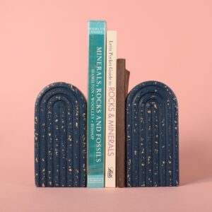 Two navy blue and beige terrazzo arched bookends either side of a group of books.