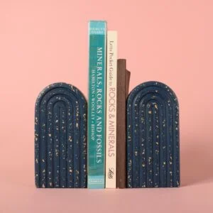 Two navy blue and beige terrazzo arched bookends either side of a group of books. By Ilex Home