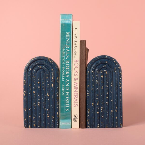 Two navy blue and beige terrazzo arched bookends either side of a group of books - Ilex Studios Co. / Ilex Home