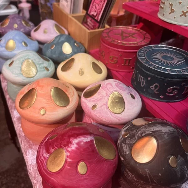 A close up photo of 10 mushroom shaped jars in every colour of the rainbow.