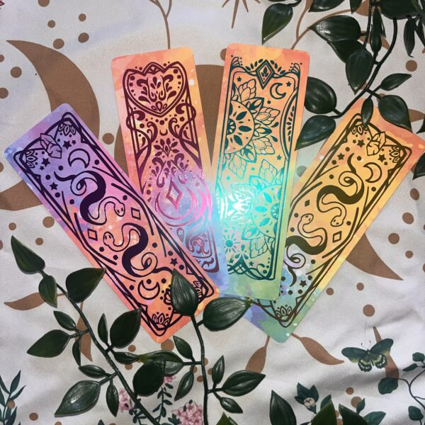 A photo of 4 bookmarks with imagery of snakes, mandalas and pretty patterns in teal, pink, purple and gold