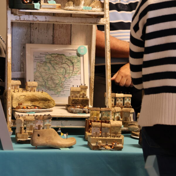 Customer browsing small house sculptures made out of wood at Tissington Craft Fair in Derbyshire, Tissington Craft Fairs