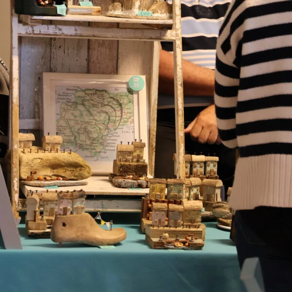 Customer browsing small house sculptures made out of wood at Tissington Craft Fair in Derbyshire, Tissington Craft Fairs