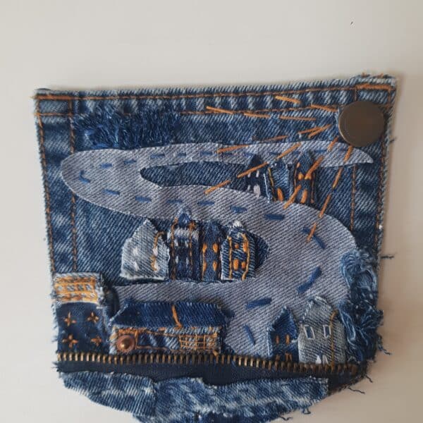 Mae-Kandoo-Denim-pocket-embellished-with-applique-and-hand-embroidered-hillside-houses-all-in-denim