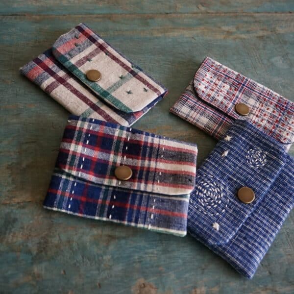 Four fabric card holders on the table, all made from vintage fabrics with front button closure and decorative hand stitches on the fabrics.