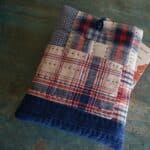 a patchwork booksleeve with a chinese knot button on top placed on a wooden surface