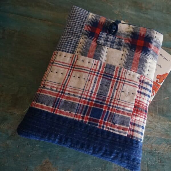 a patchwork booksleeve with a chinese knot button on top placed on a wooden surface