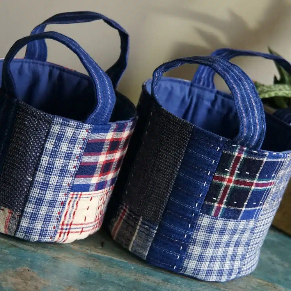 two fabric round basket with patchwork design on wooden surface