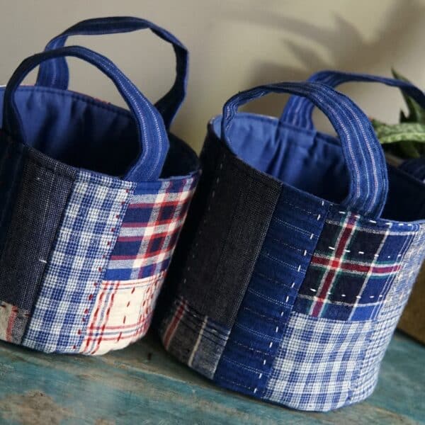 two fabric round basket with patchwork design on wooden surface