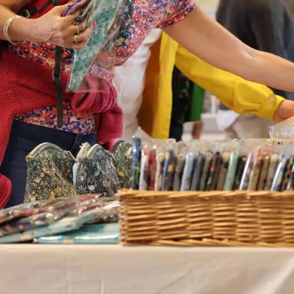 Customers are choosing sewing items at Tissington Craft Fair in Derbyshire. You can also see a basket containing more items in the foreground. Tissington Craft Fairs