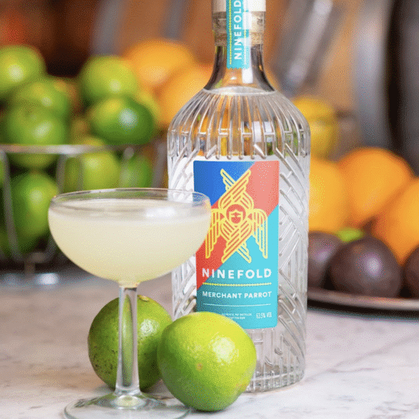 A bottle of spiced rum with a cocktail and limes at the next Wylde Thistle artisan market