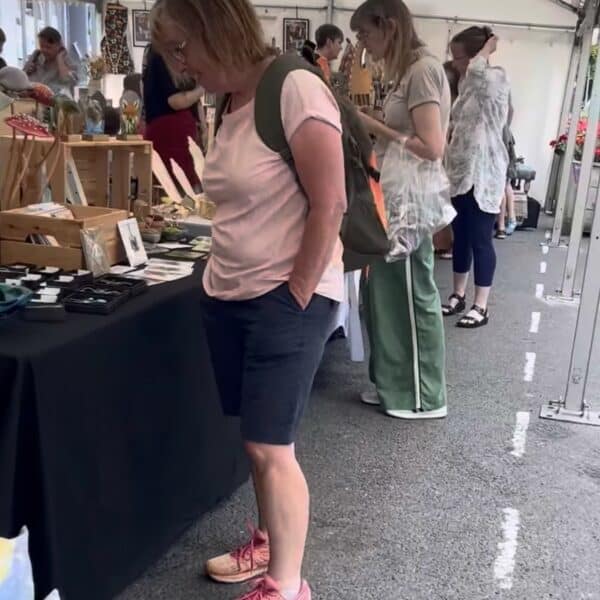 the image shows happy customers buying arts and crafts from local makers,, under a marquee