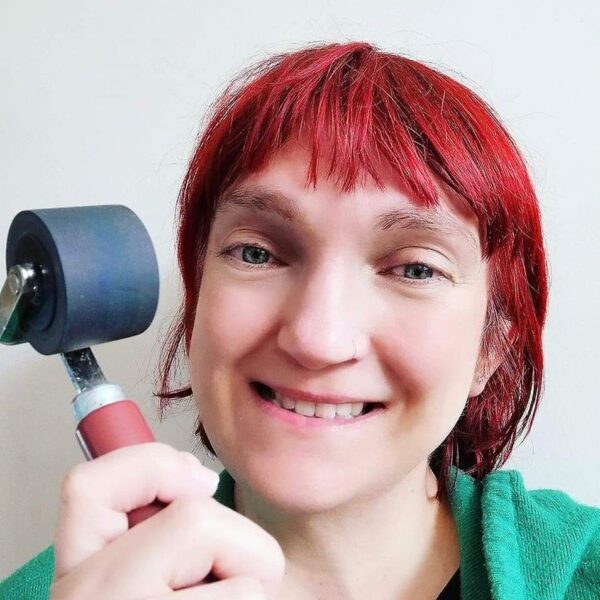 Photo of the artist holding a lino printing inking roller