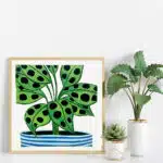 colourful spotty prayer plant lino print in wooden frame next to real plants