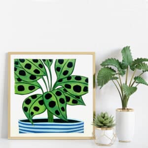 colourful spotty prayer plant lino print in wooden frame next to real plants